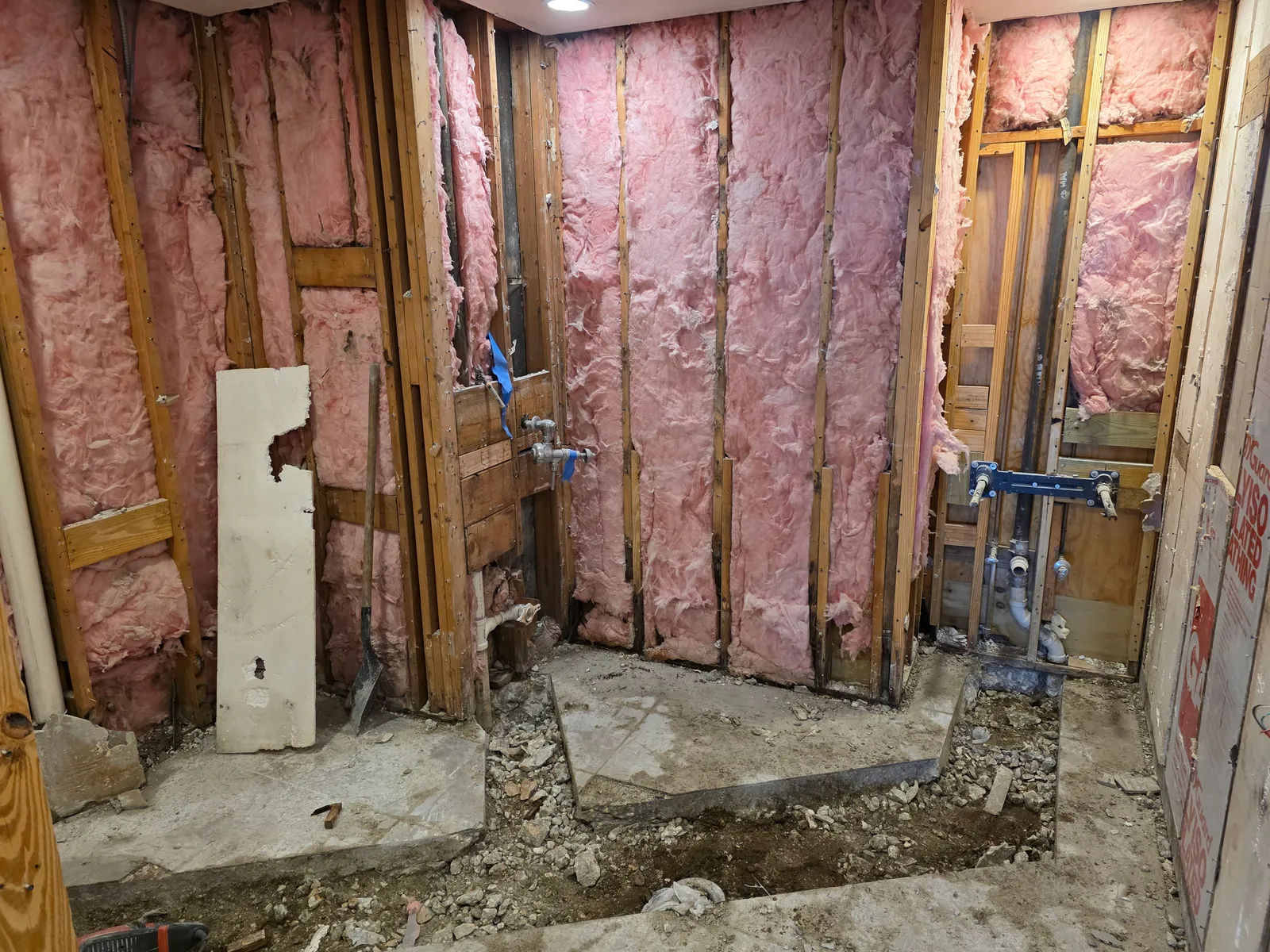 Open walls exposing plumbing access for commercial bathroom repipe